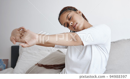 Health, wellness and zen, woman stretching on bed in the morning to start new day. Motivation to get up, young student stretching before going to school. Mental preparation in the bedroom to wake up. 94988397