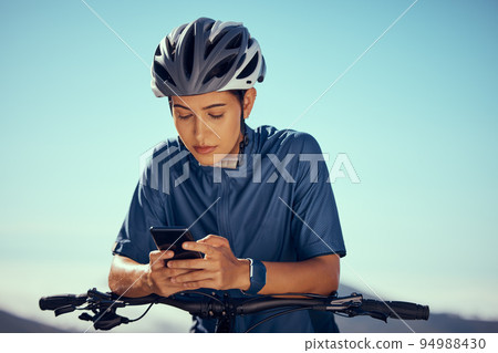 Woman on bicycle, search gps on smartphone with outdoor 5g internet and mobile application. Young bike cyclist checking location online on modern technology, fitness training for triathlon race Woman on bicycle, search gps on smartphone with outdoor 5g internet and mobile application. Young bike cyclist checking location online on modern technology, fitness training for triathlon race 94988430