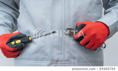 一個穿著工作服的男人,拿著扳手和螺絲刀 一個穿著工作服的男人,拿著扳手和螺絲刀 94988784
