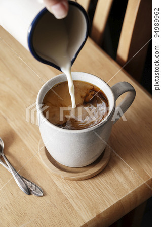 Coffee cup. Pouring milk in coffee mug, morning hot drink. Lifestyle drink photo Coffee cup. Pouring milk in coffee mug, morning hot drink. Lifestyle drink photo 94989962