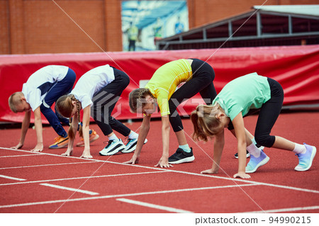 Start. Group of kids getting ready to run on treadmill at the stadium or arena. Little boys, girls in sportswear training as athletes outdoor. Concept of sport, achievements, studying, skills 94990215