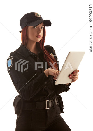 Redheaded female police officer is posing for the camera isolated on white background. 94990216
