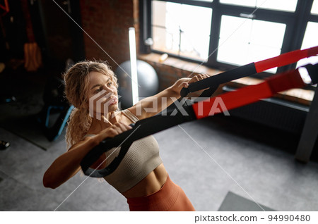 Woman doing arm exercises with trx suspension straps Woman doing arm exercises with trx suspension straps 94990480