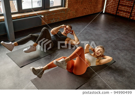 Man and woman doing abs exercise at group training class Man and woman doing abs exercise at group training class 94990499
