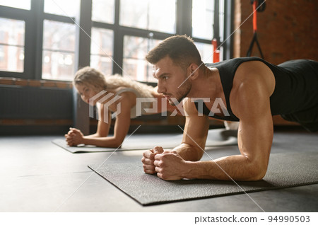 Man and woman standing in plank training at sport club gym Man and woman standing in plank training at sport club gym 94990503