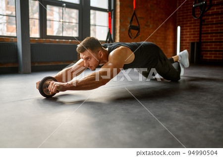 Man training with bare torso abs wheel Man training with bare torso abs wheel 94990504