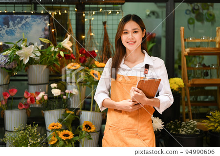 Confident small business owner standing in front of flower shop and smiling to camera. Floristry, business and technology concept Confident small business owner standing in front of flower shop and smiling to camera. Floristry, business and technology concept 94990606