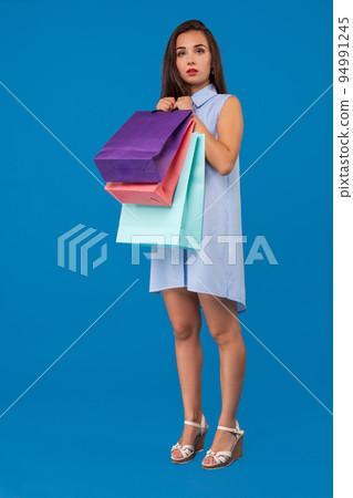 Photo of beautiful young woman with colorful shopping bags on the wonderful blue background 94991245