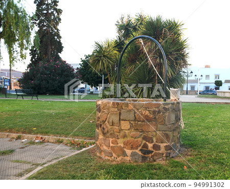 Well to draw water made of stone decorating the garden Well to draw water made of stone decorating the garden 94991302