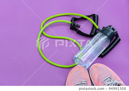 Sneakers, fit tube and a purple fitness mat. Sport concept. Copy-space Sneakers, fit tube and a purple fitness mat. Sport concept. Copy-space 94991308