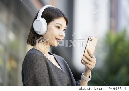 Young woman wearing headphones looking at smartphone screen 94992844