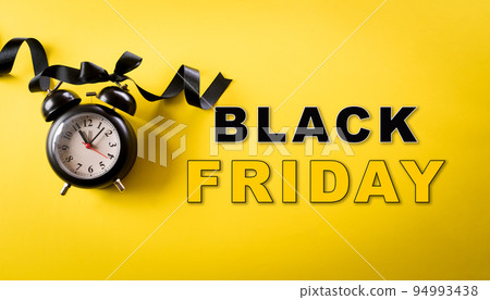 Top view of black alarm clock on yellow background. Shopping concept boxing day and Black Friday composition. 94993438