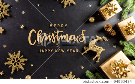 Christmas and new year background concept. Top view of Christmas gift box, spruce branches, pine cones, reindeer, christmas ball and snowflake on black wooden background. 94993454
