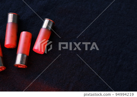 Shotgun shells on a black surfaceshotgun, shot, fire, firearm, shell, gun, weapon, ammo, powder, hunt, ammunition, bra. Ammunition for 12 gauge smoothbore weapons. Hunting ammunition. Dark background. 94994219