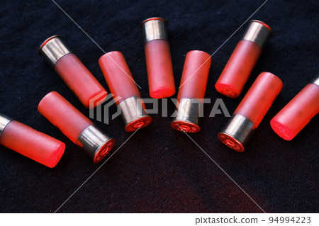 Shotgun shells on a black surface. Ammunition for 12 gauge smoothbore weapons. Hunting ammunition. Dark background. 94994223