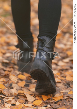 women's feet legs step. autumn walks in the park on orange foliage, healthy lifestyle 94994287