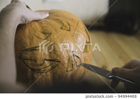 preparation for the holiday. The process of carving a Halloween pumpkin on the table preparation for the holiday. The process of carving a Halloween pumpkin on the table 94994408