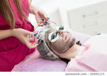 A woman is put on protective glasses during the carbon peeling procedure A woman is put on protective glasses during the carbon peeling procedure 94995133