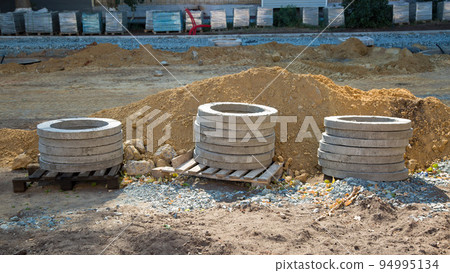 Reinforced concrete rings lie on pallets at the construction site Reinforced concrete rings lie on pallets at the construction site 94995134