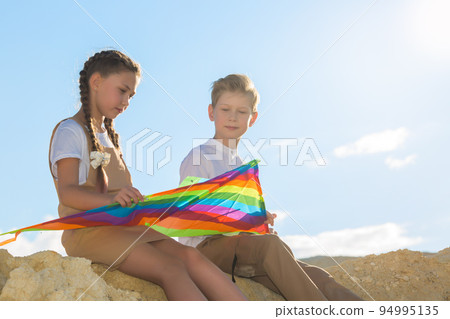 Teenage friends met in nature, talking and collecting a kite Teenage friends met in nature, talking and collecting a kite 94995135