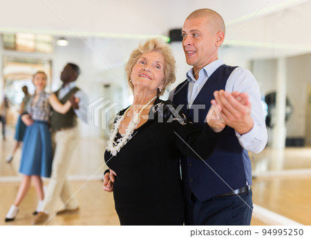 Elderly woman learning ballroom dancing movements in pair 94995250