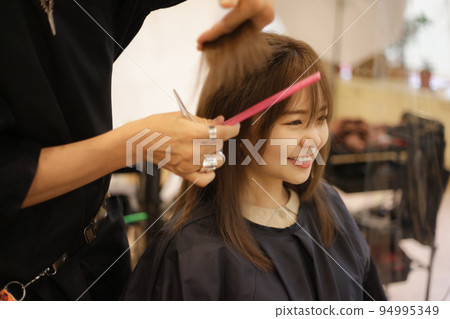 Male hairdresser cutting woman's hair Male hairdresser cutting woman's hair 94995349