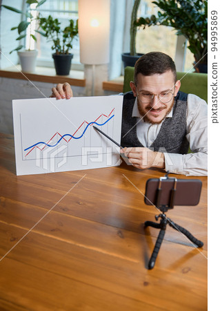 Close up male hands with pen pointing on business chart and mobile phone. People working with charts. Stock market exchange, businessman concept. Job at the desk. Online connection Close up male hands with pen pointing on business chart and mobile phone. People working with charts. Stock market exchange, businessman concept. Job at the desk. Online connection 94995869