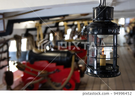 Historirical retro metal flashlight in front of cannon on battle sailing vessel Historirical retro metal flashlight in front of cannon on battle sailing vessel 94996452