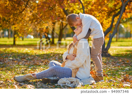 little son hugs his pregnant mom on the nature 94997346