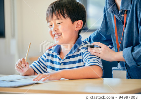 Elementary school boy writing in a notebook Elementary school boy writing in a notebook 94997808