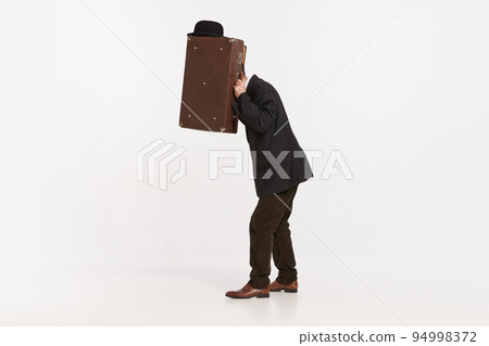 Portrait of stylish man in brown suit covering face with briefcase isolated over white studio background 94998372
