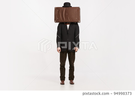 Portrait of stylish man in brown suit covering face with briefcase isolated over white studio background 94998373