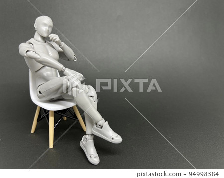一個會思考的娃娃坐在椅子上,一個會思考的人的概念。 一個會思考的娃娃坐在椅子上,一個會思考的人的概念。 94998384