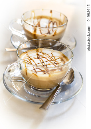 Tempting caramel latte coffees on white background Tempting caramel latte coffees on white background 94998645