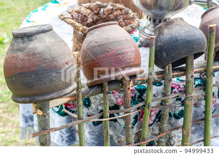 Vintage handmade ceramic pots hanging on a wooden hedge 94999433