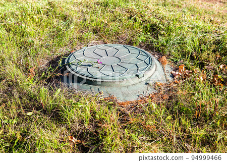 Covered sewer manhole of rural septic tank with green plastic cover Covered sewer manhole of rural septic tank with green plastic cover 94999466