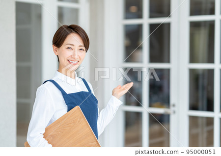 Middle-aged woman welcoming customers in front of a cafe Middle-aged woman welcoming customers in front of a cafe 95000051