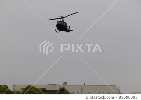 Ground Self-Defense Force UH-1 utility helicopter flying over buildings 95000393