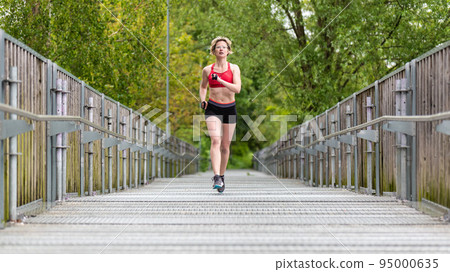 Attractive thirty year old woman in shorts and sports bra running Attractive thirty year old woman in shorts and sports bra running 95000635