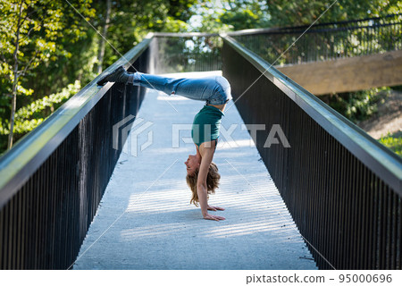 Athletic pose of an attractive 22 yo blonde girl on a pedestrian bridge Athletic pose of an attractive 22 yo blonde girl on a pedestrian bridge 95000696