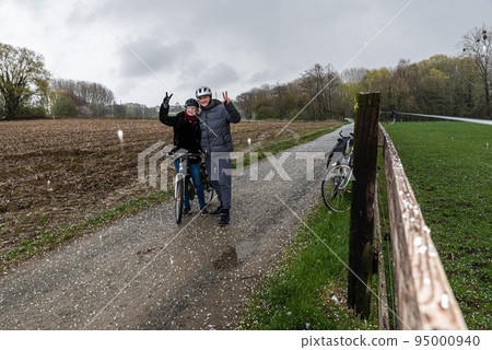 Bicycle couple posing in the hail with their bikes in the nature fields 95000940