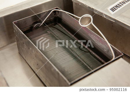 Scientist staining microscope slides for cytology studies in the laboratory. Fixation of samples through ethanol bathing. 95002116