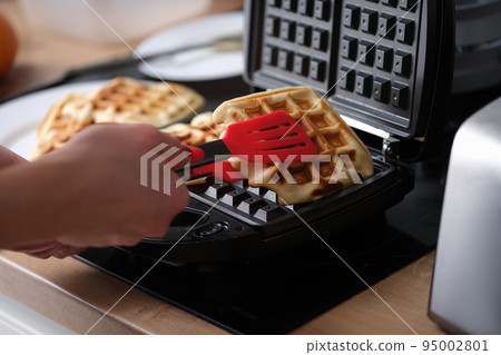 Belgian waffles in waffle iron in kitchen 95002801