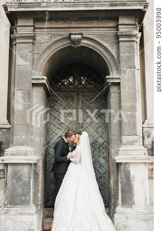 Lovely wedding couple kissing in the old city Lovely wedding couple kissing in the old city 95003998