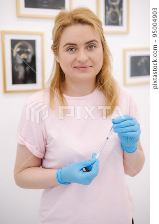 Porttait of female cosmetoloist injectionist hold syringe in hands. 95004903