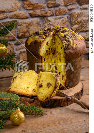 Traditional Italian Christmas Cake Panettone with green bow with cut piece of cake on rustic wooden background Traditional Italian Christmas Cake Panettone with green bow with cut piece of cake on rustic wooden background 95004959