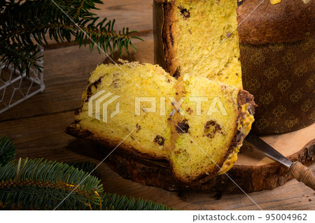 Piece of Traditional Italian Christmas Cake Panettone with green bow on wooden rustic background, close up Piece of Traditional Italian Christmas Cake Panettone with green bow on wooden rustic background, close up 95004962
