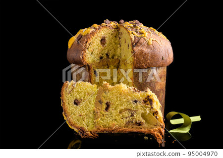 Traditional Italian Christmas Cake Panettone with green bow with cut piece of cake isolated on black background Traditional Italian Christmas Cake Panettone with green bow with cut piece of cake isolated on black background 95004970