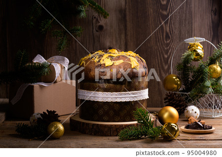 Traditional Italian Christmas Cake Panettone with white ribbon and festive decoration on wooden rustic background Traditional Italian Christmas Cake Panettone with white ribbon and festive decoration on wooden rustic background 95004980