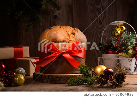 Traditional Italian Christmas Cake Panettone with red bow and festive decoration on wooden rustic background Traditional Italian Christmas Cake Panettone with red bow and festive decoration on wooden rustic background 95004982